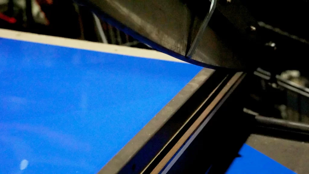 Shim sheet with blue protective film feeding into a guillotine